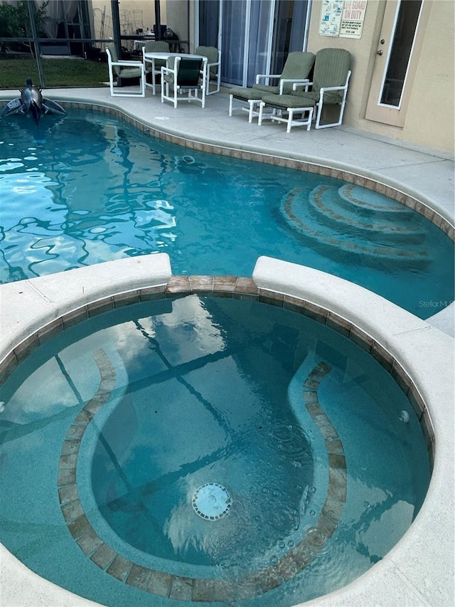 view of swimming pool featuring an in ground hot tub