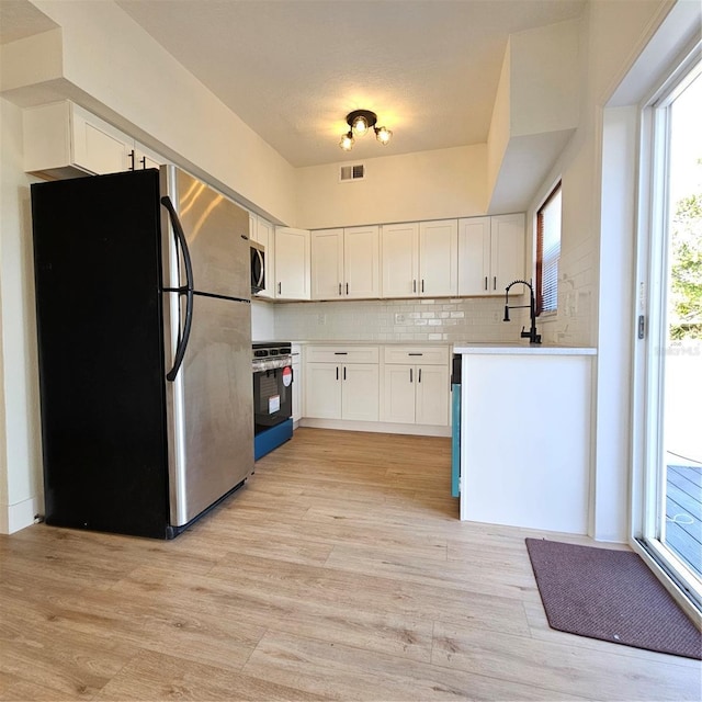 kitchen featuring backsplash, plenty of natural light, white cabinetry, and stainless steel appliances