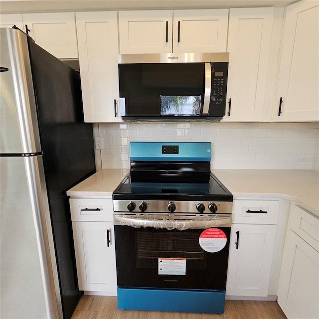 kitchen featuring tasteful backsplash, white cabinets, stainless steel appliances, and light wood-type flooring