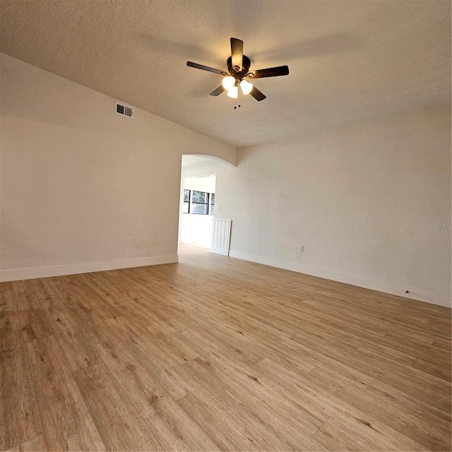 spare room featuring ceiling fan, light hardwood / wood-style floors, and a textured ceiling