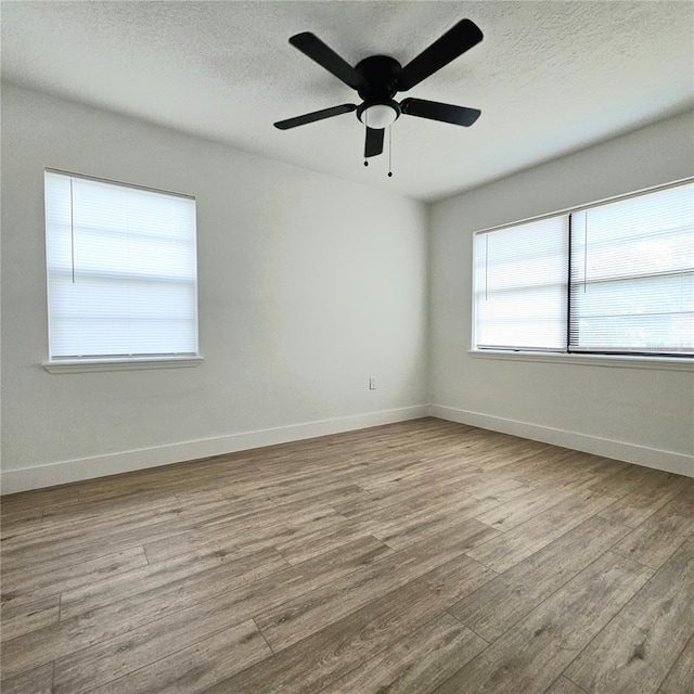 spare room featuring ceiling fan, light hardwood / wood-style flooring, and a textured ceiling