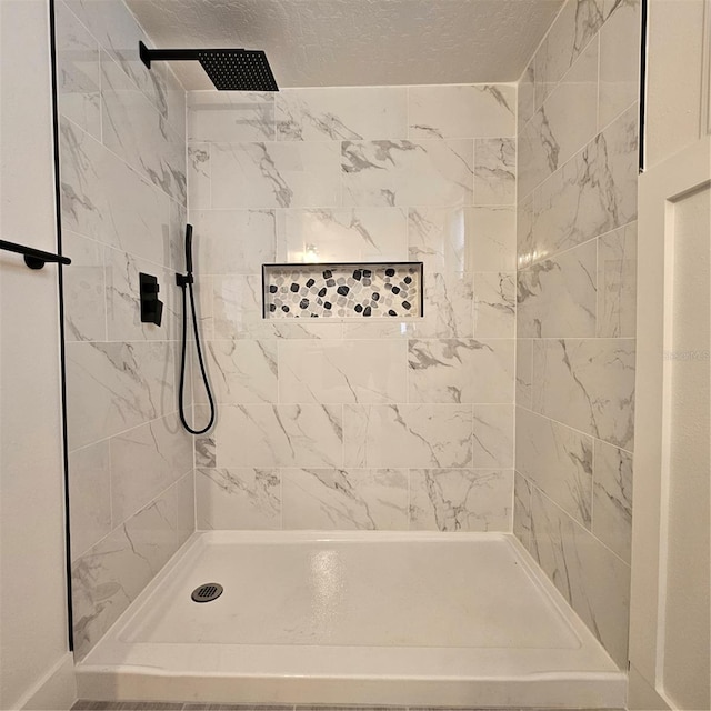 bathroom featuring a tile shower and a textured ceiling