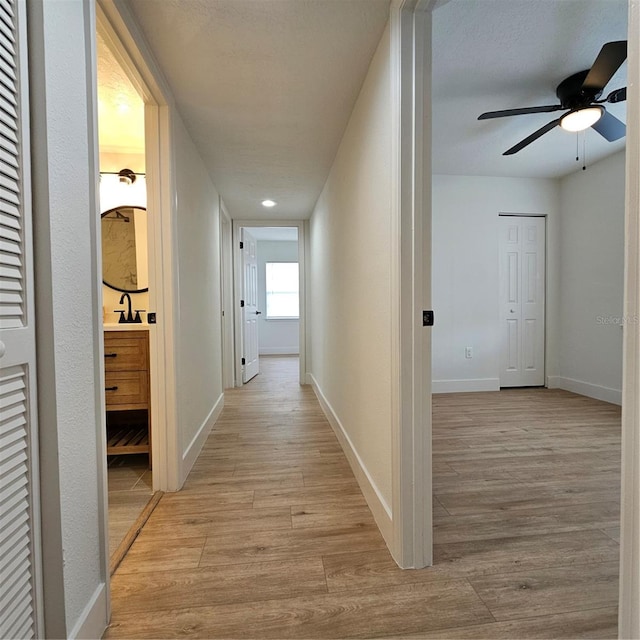 corridor with light hardwood / wood-style floors and sink