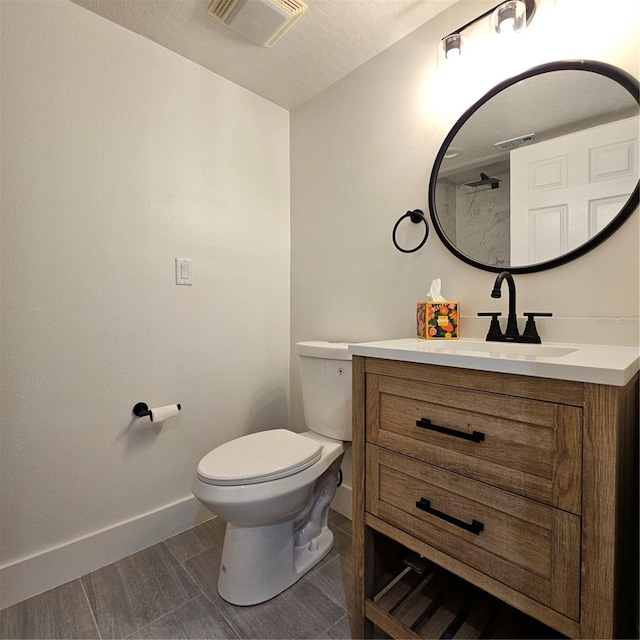 bathroom with vanity, toilet, and a textured ceiling