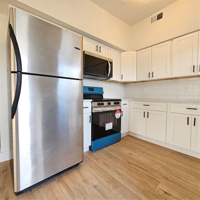 kitchen featuring decorative backsplash, white cabinetry, light hardwood / wood-style flooring, and appliances with stainless steel finishes