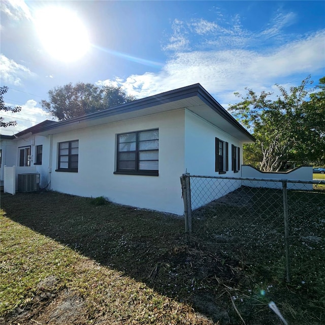 view of side of home with central AC unit and a lawn