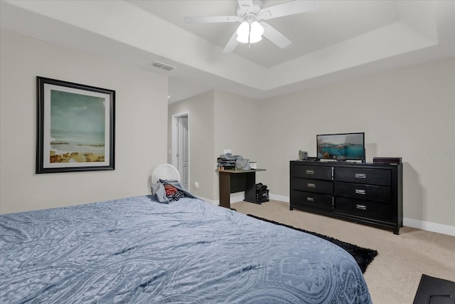 carpeted bedroom with ceiling fan and a raised ceiling