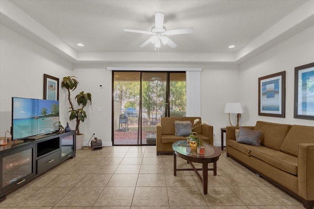 living room featuring ceiling fan, light tile patterned flooring, and a tray ceiling