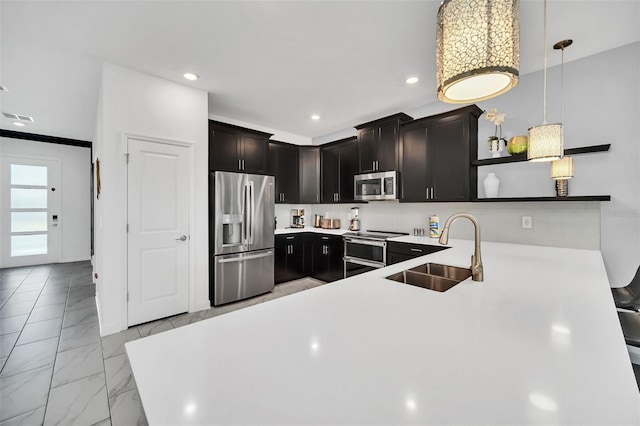 kitchen with dark brown cabinetry, sink, hanging light fixtures, stainless steel appliances, and kitchen peninsula