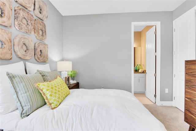 bedroom featuring ensuite bathroom and light carpet