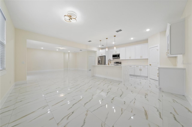 kitchen with stainless steel appliances, sink, a center island with sink, white cabinetry, and hanging light fixtures