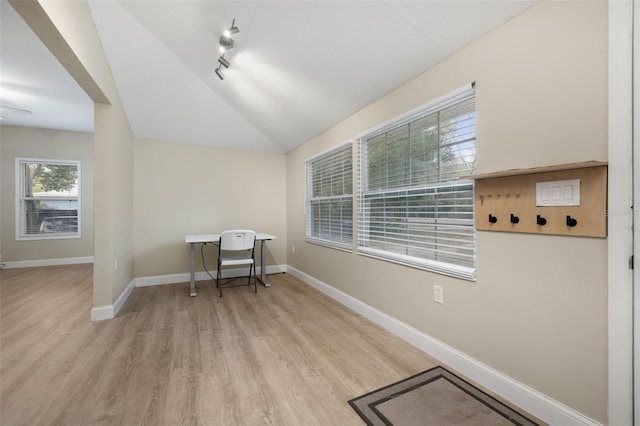 office with rail lighting, vaulted ceiling, and light wood-type flooring