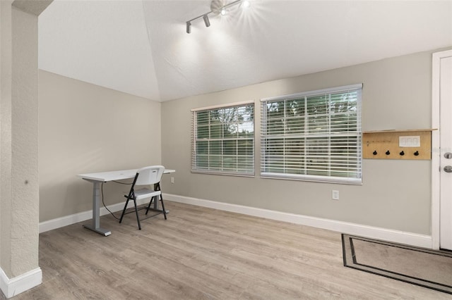 office space with light wood-type flooring, lofted ceiling, and track lighting