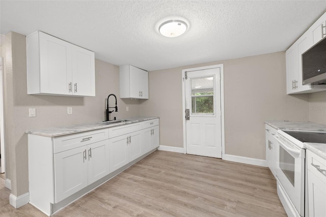 kitchen featuring electric range, white cabinetry, sink, and a textured ceiling