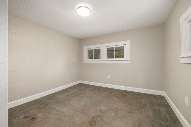 unfurnished room featuring dark colored carpet