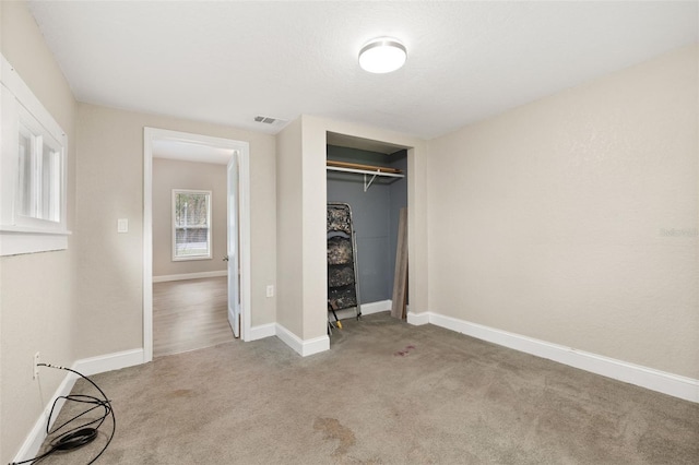 unfurnished bedroom with light carpet and a closet