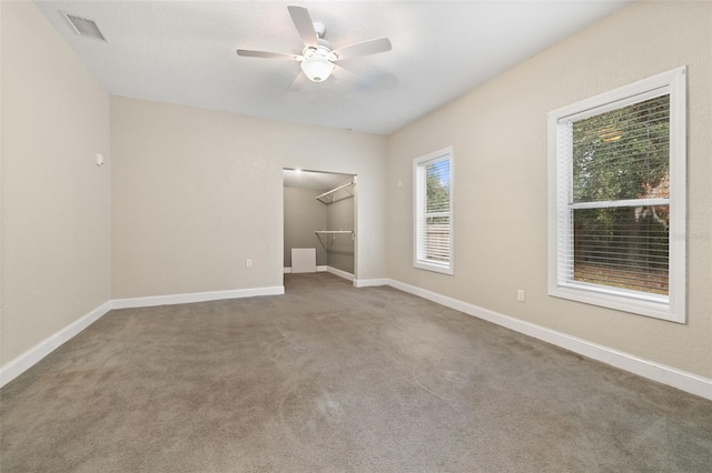 unfurnished bedroom featuring carpet, a spacious closet, a closet, and ceiling fan