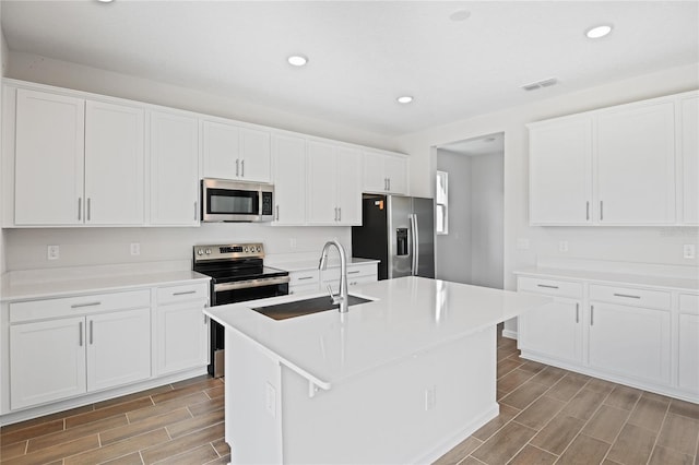 kitchen with white cabinets, sink, an island with sink, and stainless steel appliances