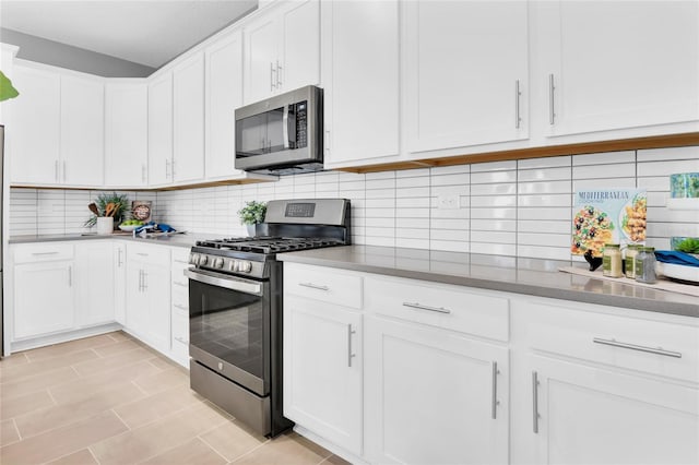 kitchen featuring white cabinets, appliances with stainless steel finishes, decorative backsplash, and light tile patterned flooring