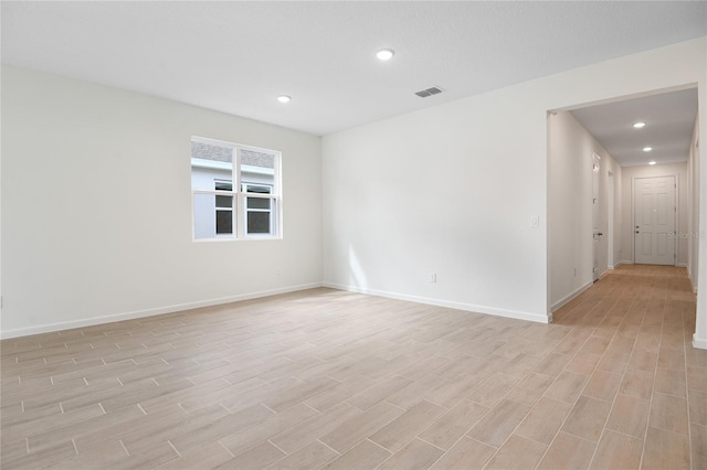 spare room featuring light wood-type flooring, baseboards, visible vents, and recessed lighting