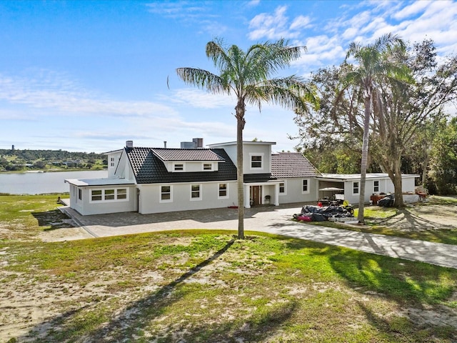 back of property with a lawn and a water view