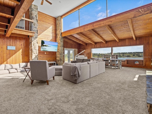 carpeted living room featuring lofted ceiling with beams, wood walls, ceiling fan, and wood ceiling