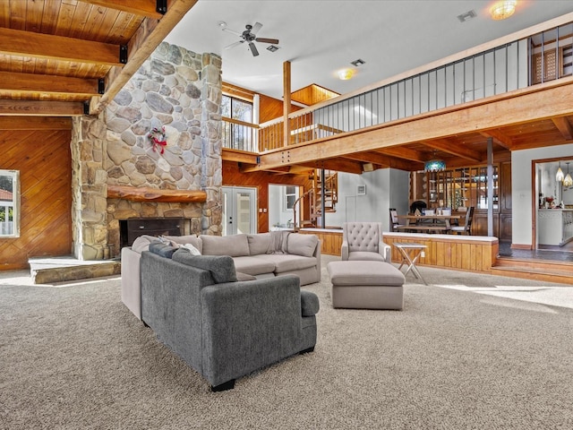 living room featuring carpet flooring, a fireplace, ceiling fan, and wooden walls