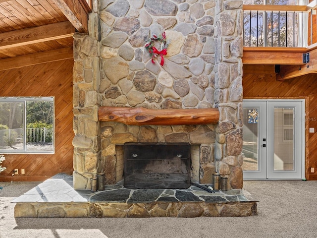 unfurnished living room with carpet flooring, wood ceiling, beam ceiling, a stone fireplace, and wood walls