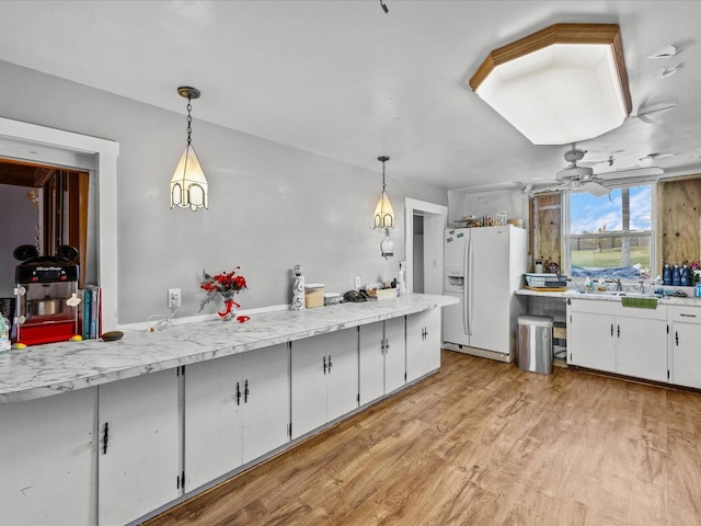 kitchen featuring white cabinets, decorative light fixtures, white fridge with ice dispenser, and light hardwood / wood-style floors