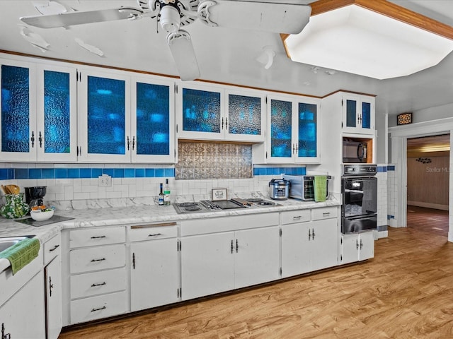 kitchen featuring white cabinets, tasteful backsplash, light hardwood / wood-style flooring, and black appliances