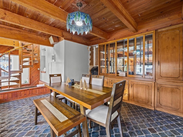 unfurnished dining area with beamed ceiling, wood walls, and wood ceiling