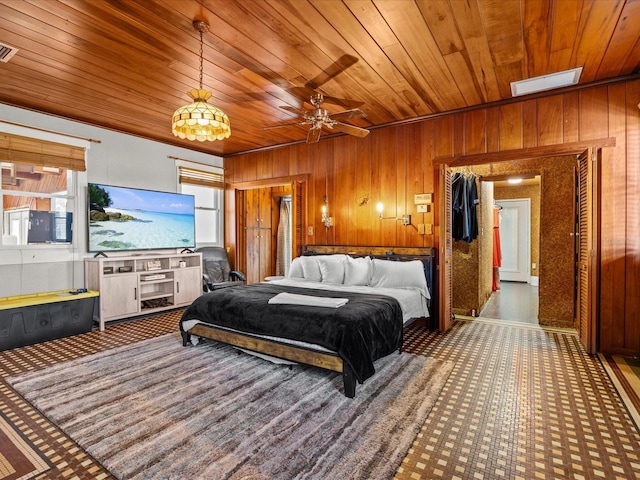 bedroom with ceiling fan, wood walls, wood ceiling, and crown molding