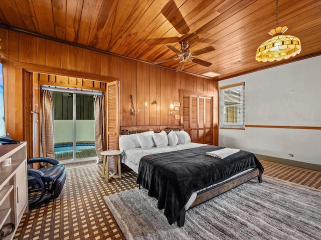 bedroom featuring access to exterior, multiple windows, ceiling fan, and wood walls