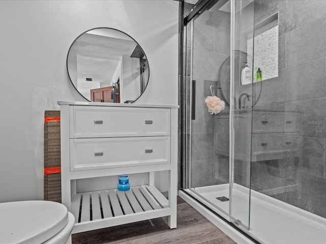 bathroom with a shower with shower door, toilet, and wood-type flooring