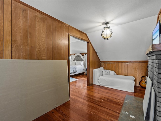 bedroom with wood walls, a fireplace, dark hardwood / wood-style floors, and vaulted ceiling