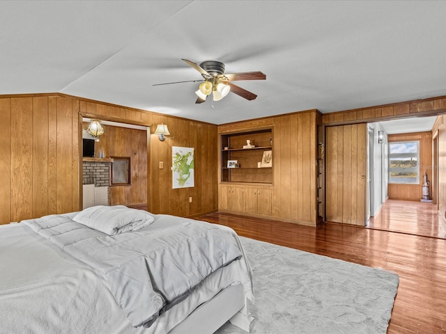 bedroom featuring hardwood / wood-style floors, ceiling fan, and wooden walls