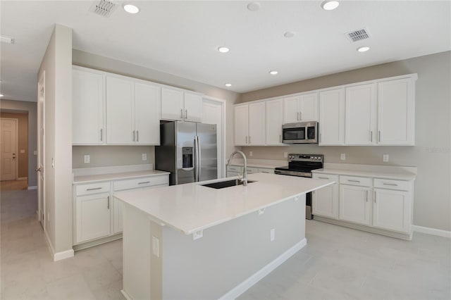 kitchen with white cabinets, sink, an island with sink, appliances with stainless steel finishes, and light tile patterned flooring