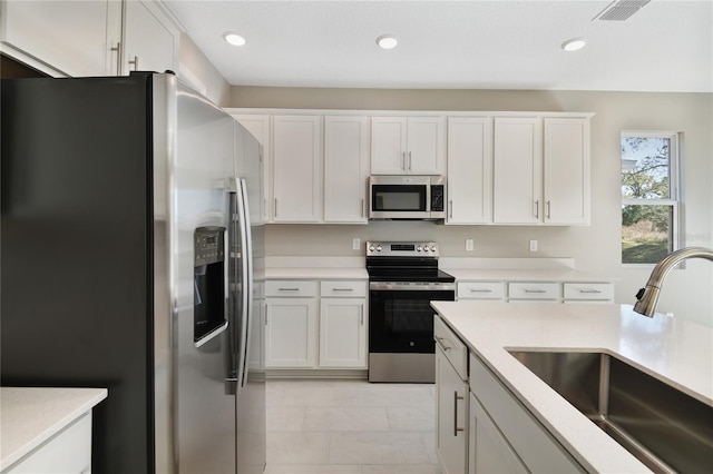 kitchen featuring light tile patterned flooring, stainless steel appliances, white cabinetry, and sink