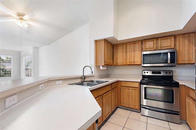 kitchen featuring kitchen peninsula, appliances with stainless steel finishes, a textured ceiling, sink, and light tile patterned flooring