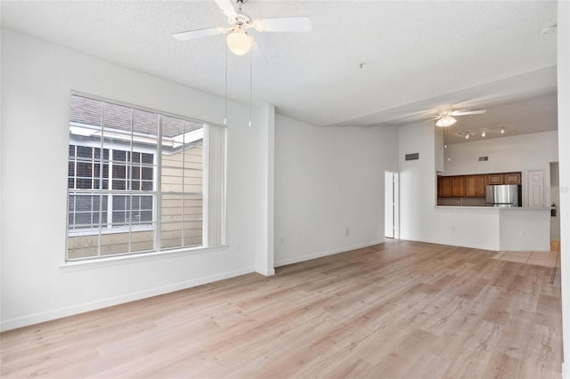 unfurnished living room featuring ceiling fan, light hardwood / wood-style floors, a textured ceiling, and a wealth of natural light