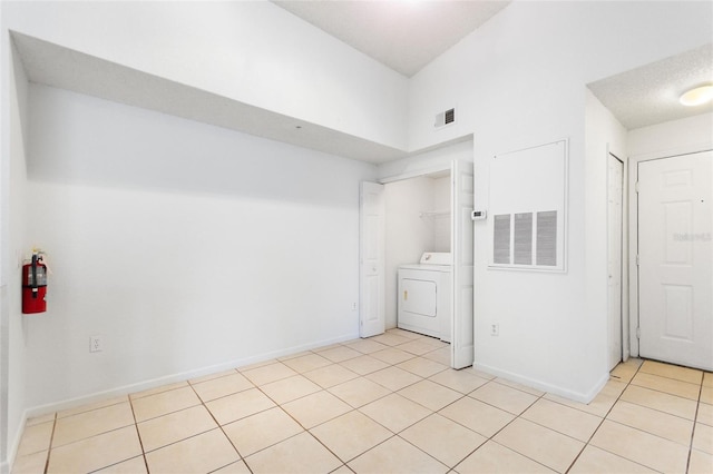 interior space with a textured ceiling, a towering ceiling, and washer / clothes dryer