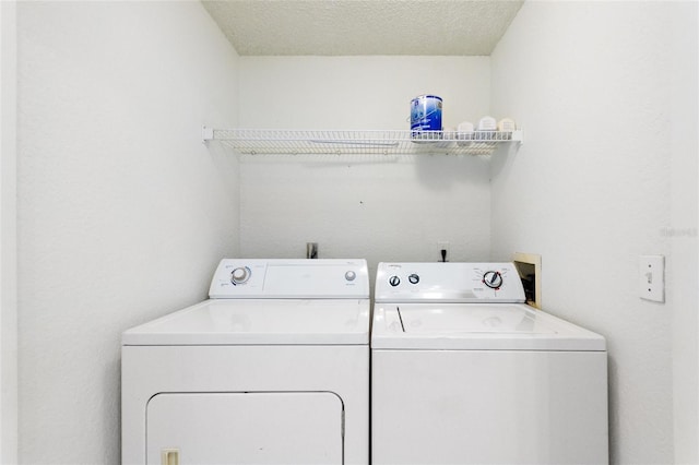 clothes washing area with washing machine and dryer and a textured ceiling