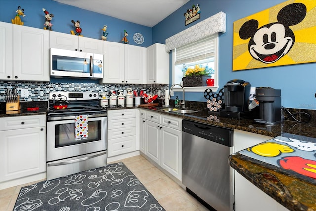 kitchen featuring dark stone counters, white cabinets, sink, light tile patterned flooring, and stainless steel appliances