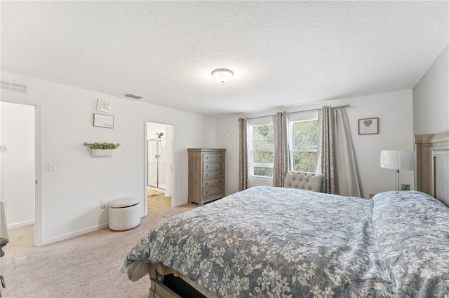 bedroom featuring light colored carpet, a textured ceiling, and ensuite bath