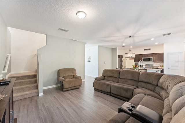 living room with light hardwood / wood-style flooring, a textured ceiling, and sink