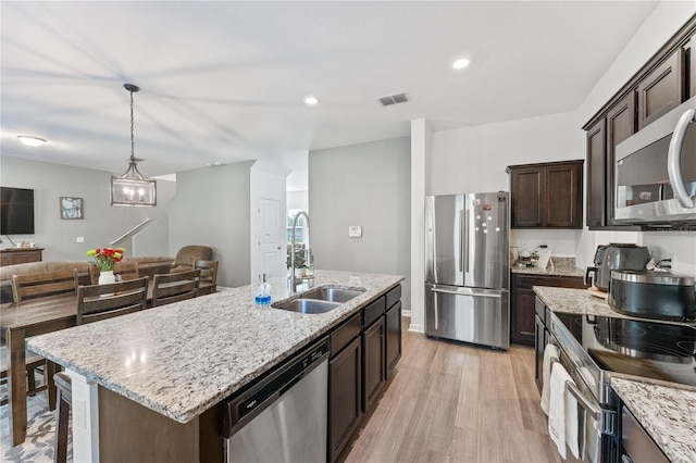 kitchen featuring light stone countertops, sink, a center island with sink, and appliances with stainless steel finishes