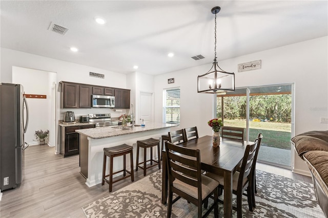 dining space featuring light hardwood / wood-style flooring, sink, and an inviting chandelier