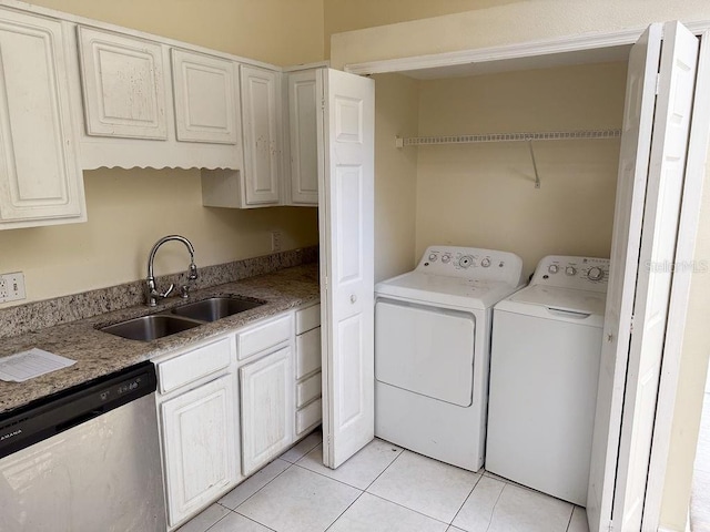 clothes washing area with sink, light tile patterned floors, and washing machine and clothes dryer