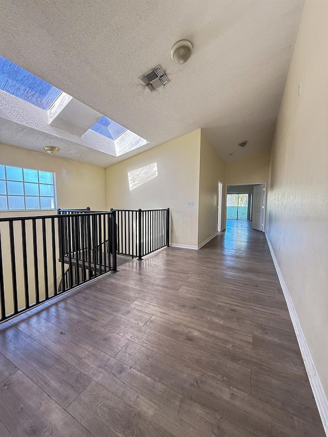 spare room with dark wood-type flooring, a textured ceiling, and a skylight