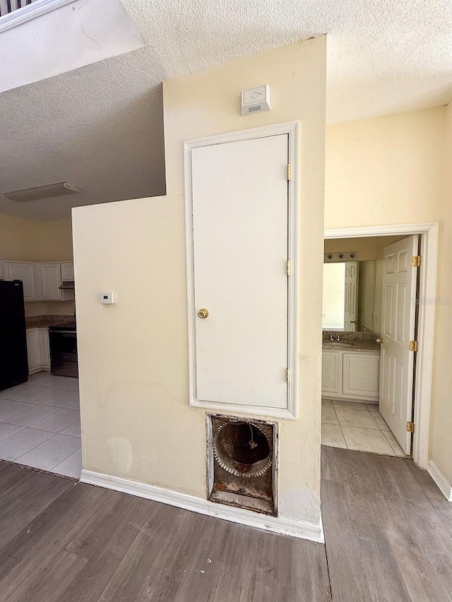 hallway with a textured ceiling and light wood-type flooring